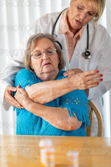 Female doctor helping senior adult woman with arm exercises