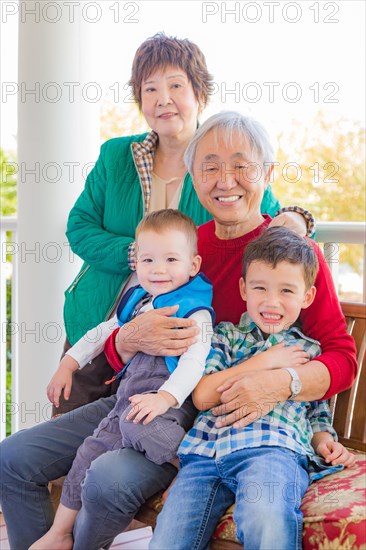 Senior adult chinese couple sitting with their mixed-race grandchildren