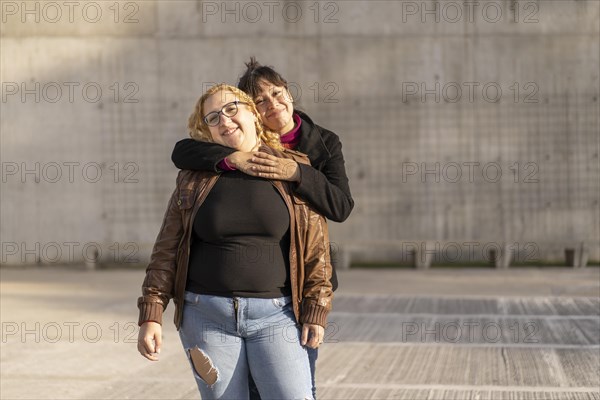 Couple of lesbian women hugging in a park looking at the camera smiling. Copy space