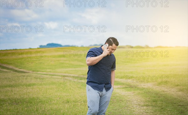 Person with his cell phone in the field talking on the phone