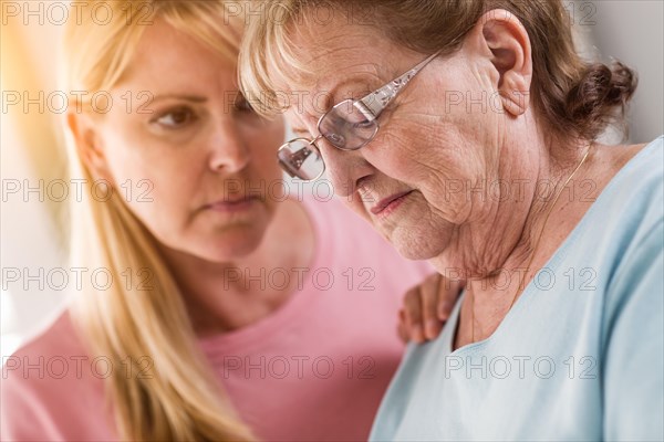 Young adult woman consoles sad senior adult female