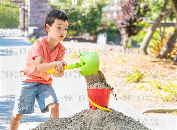 Young caucasian and chinese boy playing with shovel and bucket