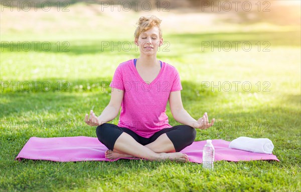 Young fit adult woman outdoors on the grass doing yoga