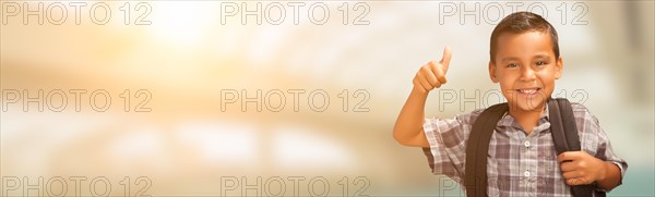 Young hispanic male child showing thumbs up wearing backpack with room for text