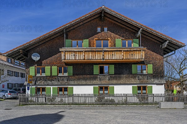 Fassade mit Holzschindeln und gruenen Fensterlaeden