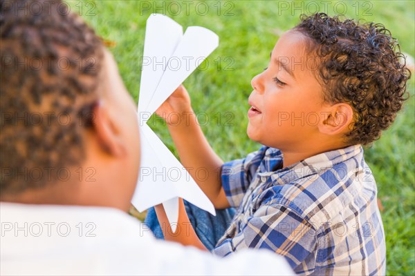 Happy african american father and mixed-race son playing with paper airplanes in the park