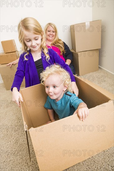 Playful young family in empty room playing with moving boxes