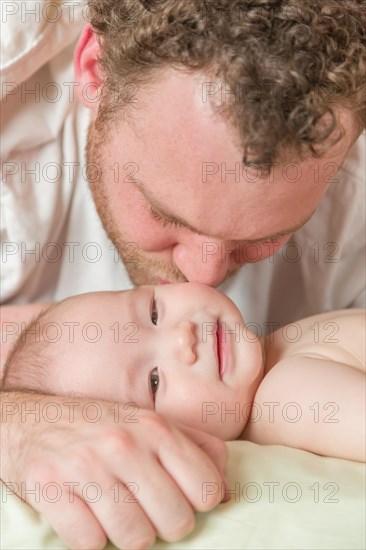 mixed-race chinese and caucasian baby boy laying in bed with his father