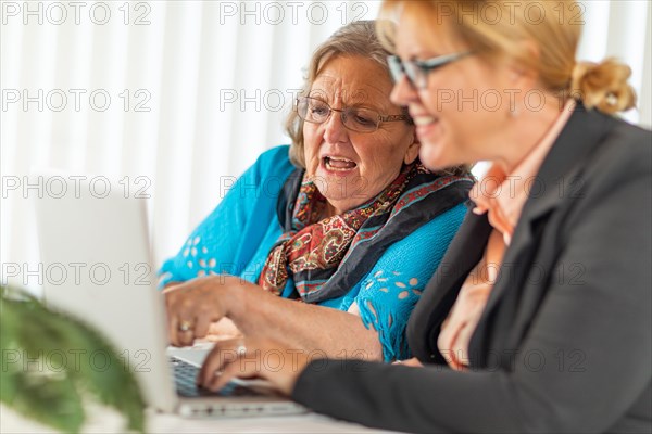 Woman helping senior adult lady on laptop computer