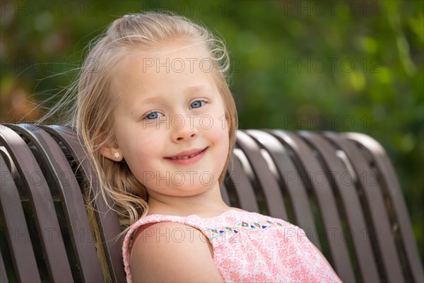 Pretty young caucasian girl portrait sitting on the bench at the park