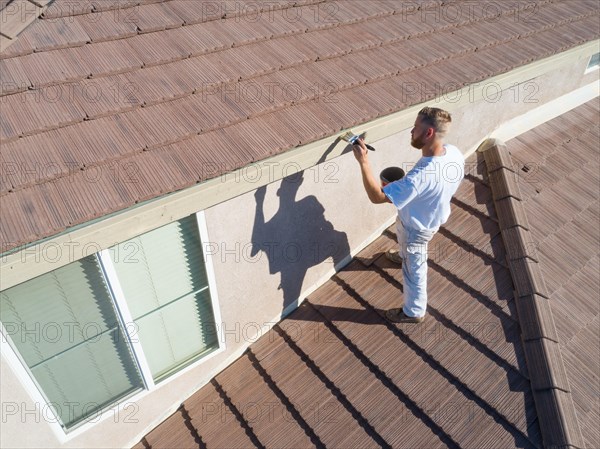 Professional painter using A brush to paint house facade