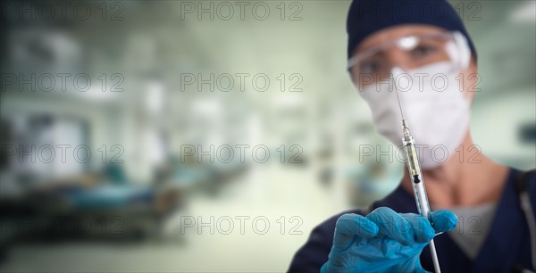 Doctor or nurse holding medical syringe with needle within hospital