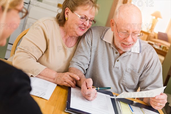 Senior adult couple going over documents in their home with agent at signing