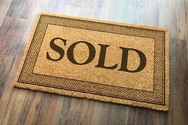 Sold welcome mat on A wood floor background