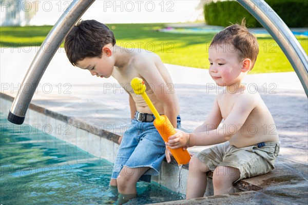Young mixed-race chinese and caucasian brothers playing at the pool