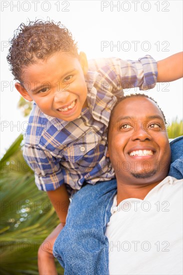 mixed-race son and african american father playing piggyback outdoors together