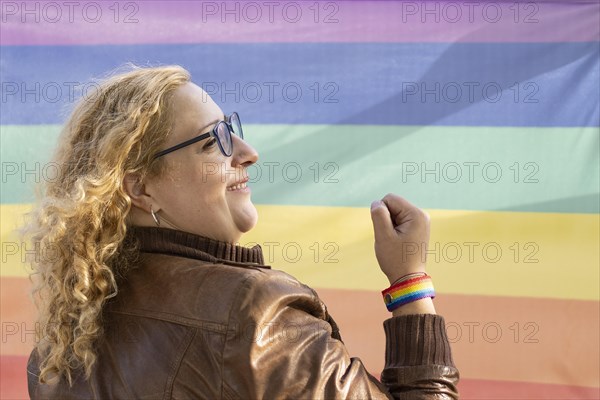 Portrait of a lesbian latin woman wearing lgbt wristband on a rainbow background