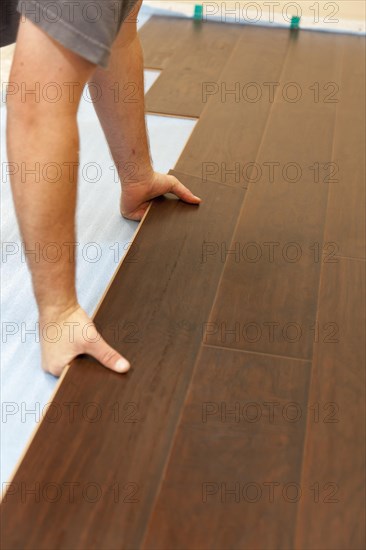 Man installing new laminate wood flooring abstract