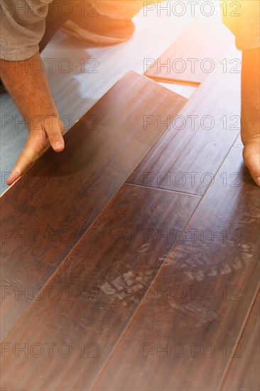 Man installing new laminate wood flooring abstract