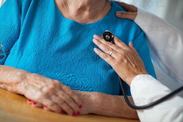 Female doctor checking the heart with stethoscope of senior adult woman