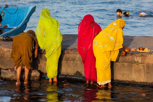 Indian women doing morning pooja on ghats of sacred Narmada river. Maheshwar