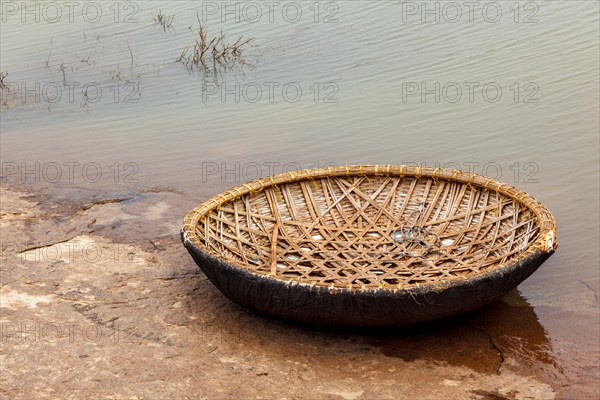 Traditional wickerwork coracle boat in Hampi on bank of Tungabhadra river