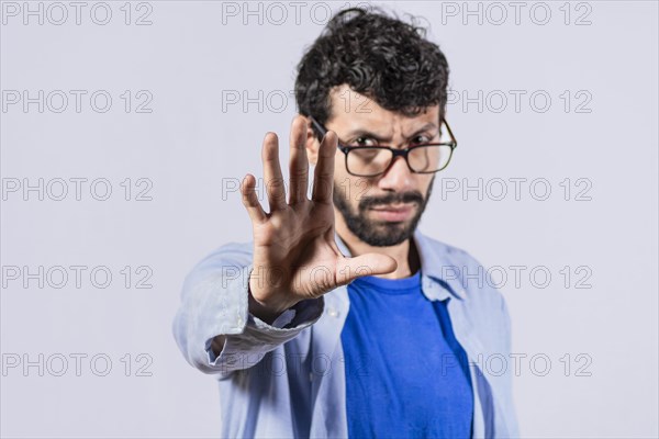 Serious young man stop sign with palm