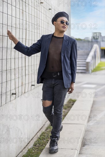 Latin gay male with makeup wearing fashion hat doing catwalk in the street