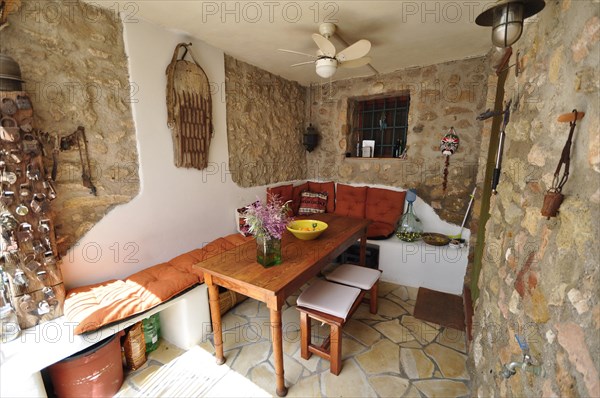 Wooden table with bench in covered dining area with natural stone wall