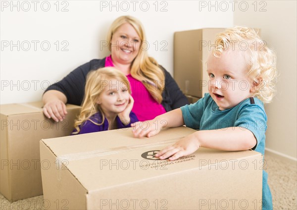 Playful young family in empty room playing with moving boxes