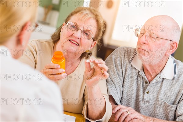 Doctor or nurse explaining prescription medicine to senior adult couple