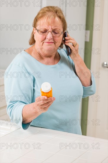 Senior adult woman on cell phone holding prescription bottle