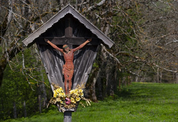 Geschnitztes Wegkreuz mit Blumenschmuck