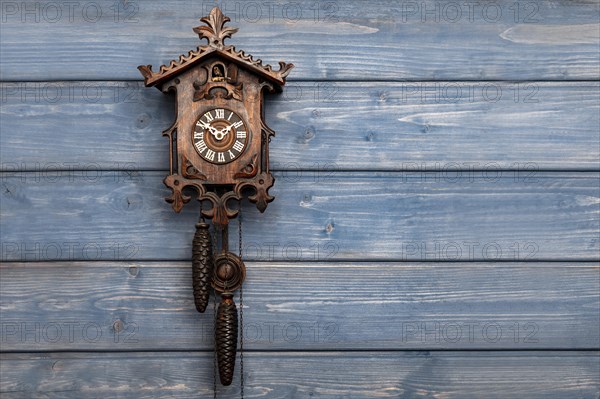 Antique Black Forest cuckoo clock in front of blue wooden wall