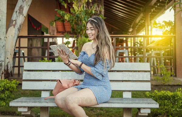 A cute girl sitting on a bench reading a book