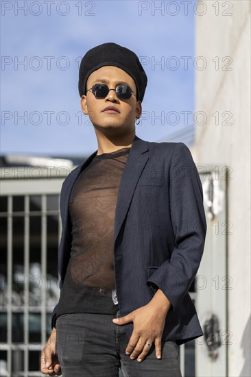 Latin gay male with makeup wearing fashion hat doing catwalk in the street