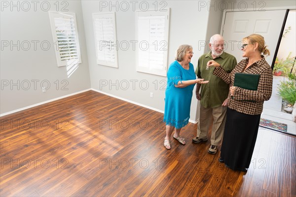 Female real estate agent handing new house keys to senior adult couple in new home