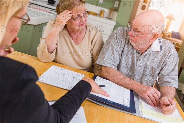 Senior adult couple going over documents in their home with agent at signing