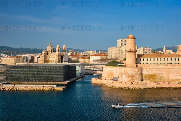 Marseille Old Port and Fort Saint-Jean and Museum of European and Mediterranean Civilisations and Marseille Cathedral on sunset with passing boat