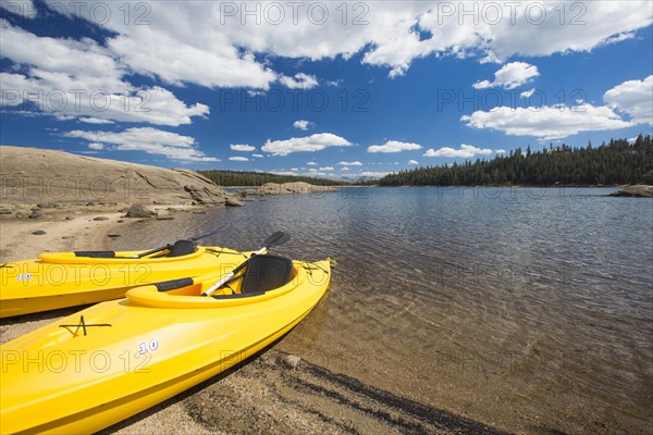 Pair of yellow kayaks on a beautiful mountain lake shore