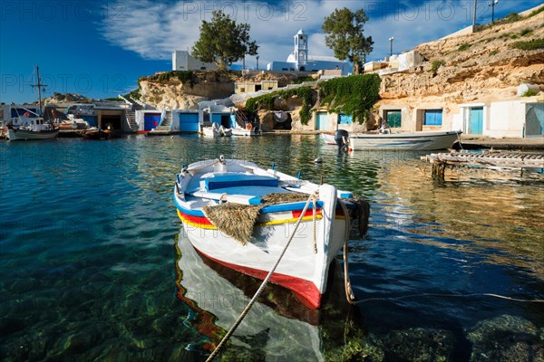 Fishing boats moored in crystal clear turquoise sea water in harbour in Greek fishing village of Mandrakia