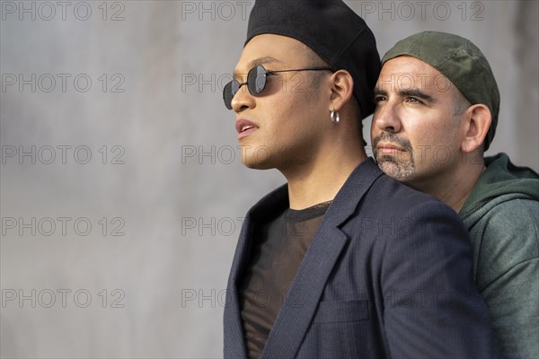 Gay latin couple wearing fashionable hats hugging in the street. Copy space