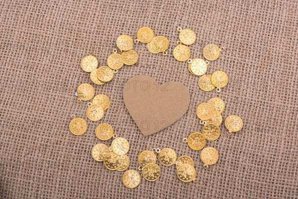 Fake gold coins around heart shape made of paper