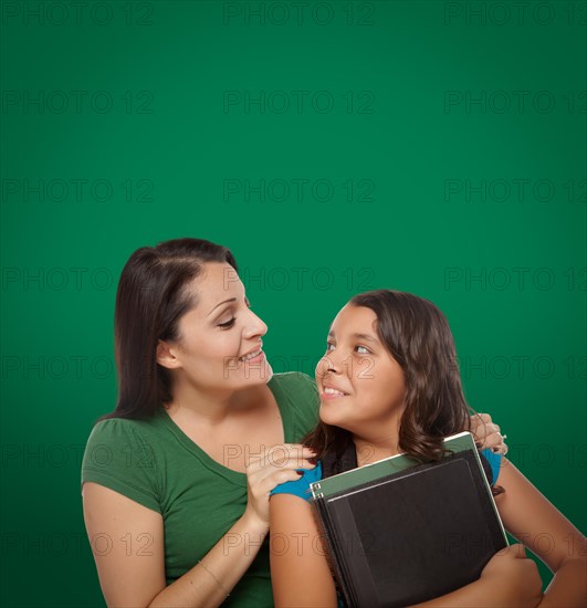 Blank chalk board behind proud hispanic mother and daughter student