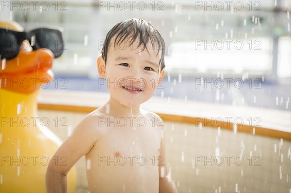 mixed-race boy having fun at the water park with large rubber duck in the background