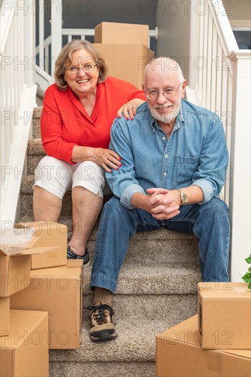 Senior couple resting on stairs surrounded by moving boxes