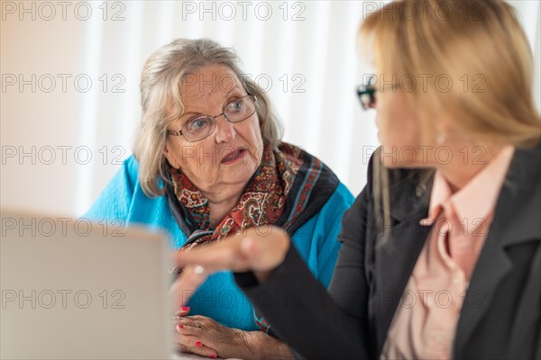 Woman helping senior adult lady on laptop computer