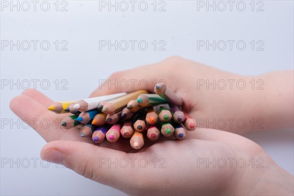 Hand holding color Pencils placed on a white background