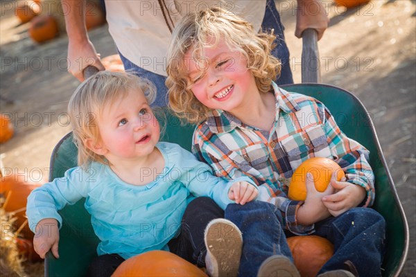 Sweet little boy plays with his baby sister in a rustic ranch setting at the pumpkin patch