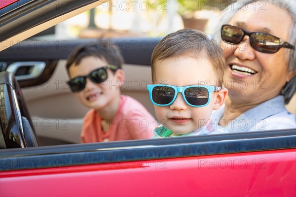 Chinese granfather and mixed-race children playing in parked car